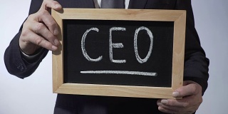 CEO写在黑板上，身着经典西装的男人举着牌子，商业战略