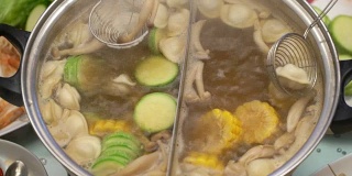 概念火锅亚洲料理。用撇子从沸腾的汤中捞出蘑菇和西葫芦饺子