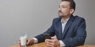 男人拿着一杯牛奶用手机上网