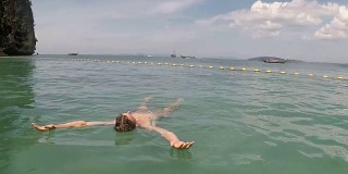 男人在海中游泳在美丽的海滩上躺在水里的年轻人行动摄像机POV
