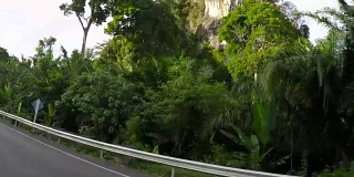 侧视图的道路驾驶通过热带森林和山脉行动摄像机POV