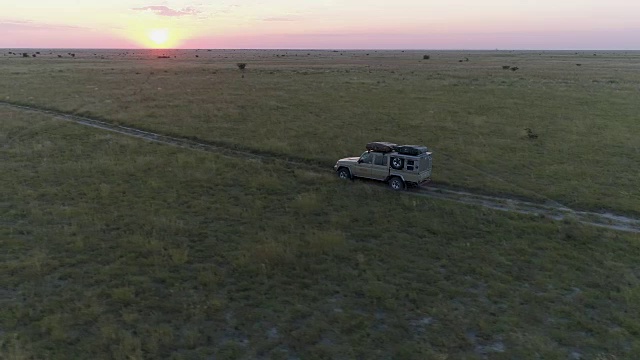 狩猎车在夕阳下穿过博茨瓦纳的草原