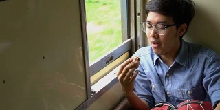 亚洲男子背包客在坐火车旅行时吃中国包子