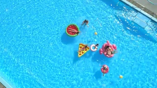 空中俯仰:健康的人们在游泳池里的充气浮子上打水仗视频素材模板下载