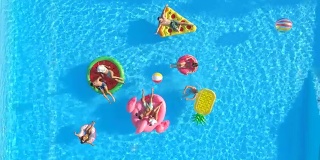 快乐的年轻朋友们在游泳池里玩着彩色的浮球