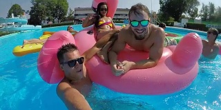 慢镜头:在泳池派对上，快乐的朋友们在有趣的浮子上自拍