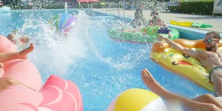 慢镜头:快乐的年轻人在五颜六色的浮子上戏水