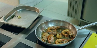 厨师在平底锅上煎皇家虾并加入葵花籽油