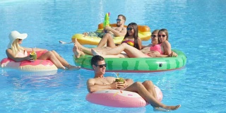 慢镜头:快乐的年轻朋友们在充气浮子上享受暑假
