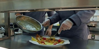 厨师用手把煮好的虾和蔬菜用酱汁放在盘子里