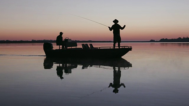 航拍背光视图的渔民飞钓鱼从一艘船