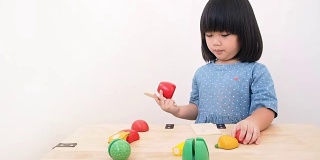 有趣的亚洲小女孩玩木制烹饪玩具，小厨师准备在厨房柜台上的食物