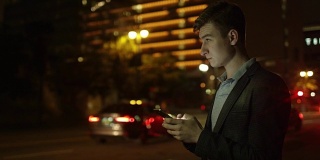 一名年轻游客晚上站在大街上发短信
