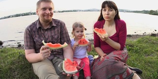 在一个夏日，一家人在池塘边野餐，一起吃西瓜