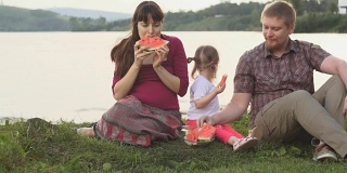 在一个夏日，一家人在池塘边野餐，一起吃西瓜