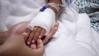 年轻的父母和生病的小女儿抱着绷带的手舒适在医院的床上视频素材模板下载