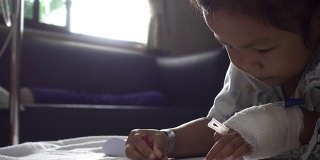 特写的童年包扎的手与颜料彩色铅笔在一张纸上医院。治疗室实时拍摄。年轻病人的放松时间。