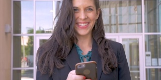 一位女性公司主管从她的移动设备上抬起头，微笑着