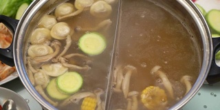 概念火锅亚洲美食。在桌上沸腾的肉汤。玉米放进肉汤里煮