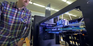 一名工程师走了过来，查看一台巨大的3d打印机开始工作。4 k。