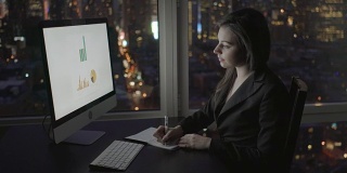在多层办公大楼里用电脑、圆珠笔、Pad和电话工作的漂亮女人。打电话给同事，透过窗户可以看到大城市。