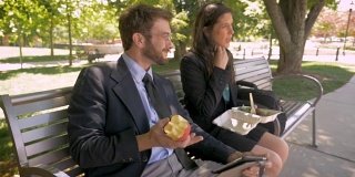 一男一女在吃健康午餐，在平板电脑上讨论一些事情