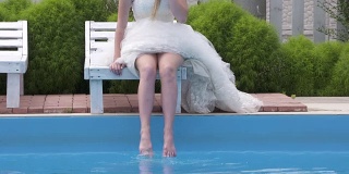 穿着白色婚纱的赤脚小女孩在游泳池旁