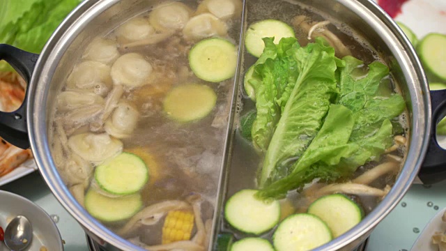 概念火锅亚洲美食。在桌上煮肉汤。沙拉放在用筷子煮的肉汤里