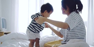 亚洲婴儿(6-11个月)男孩与母亲学习走路。