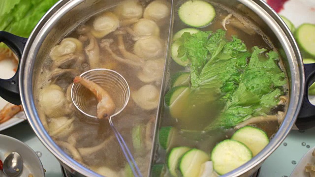 概念火锅亚洲美食。在桌上沸腾的肉汤。烹饪虾在撇勺特写