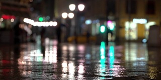 抽象明亮模糊的背景与雨滴，沥青照明路灯和交通灯。身份不明的女孩在雨夜的城市街道上。商店橱窗和街灯在潮湿的路面上发出明亮的照明和反射