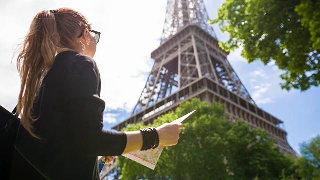 一个在阳光明媚的日子里走在巴黎街道上的女人正在欣赏埃菲尔铁塔