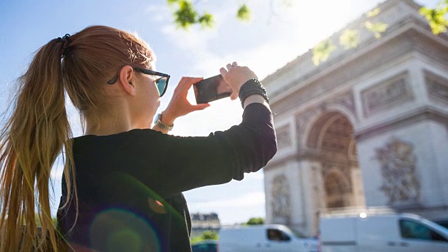 游客走在巴黎街头，拍摄凯旋门的照片