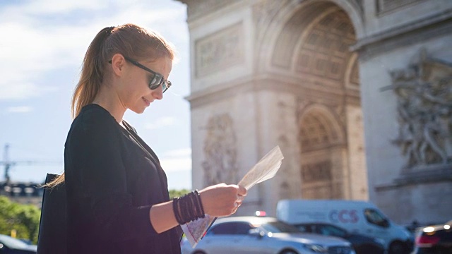 一位妇女站在著名的凯旋门前看巴黎地图
