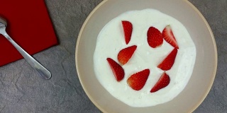 旋转碗里的酸奶和新鲜成熟的草莓块