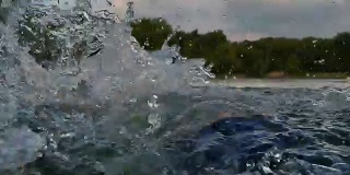 男子在背后游泳，在湖里溅水，旁边是一个十几岁的女孩。