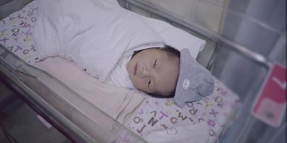 新生的亚洲婴儿睡在保温箱和婴儿毯。