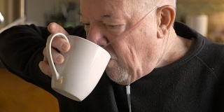 一位老人戴着氧气面罩喝着咖啡，慢动作