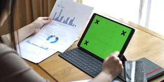 女性工作在数字平板电脑与图表，绿色屏幕