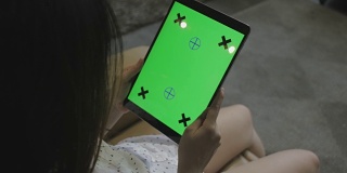 女孩在家里使用绿色屏幕的数字平板电脑