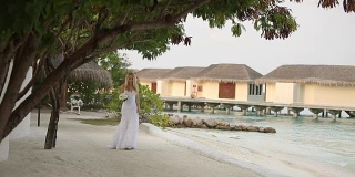 初见新婚夫妇。新娘在一个浪漫的热带小岛上，在蔚蓝的泻湖海洋附近的白色沙滩上举行婚礼
