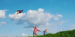 妈妈和女儿在玩风筝。沿着一个绿色的大山坡跑