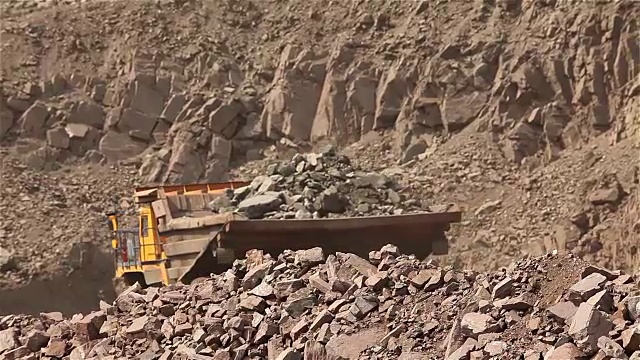 A dumper rides along the road, Yellow dump truck is in the quarry, Industrial exterior