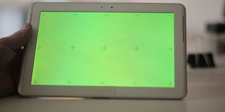 手持空白平板电脑的男子对着绿色屏幕。