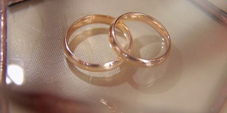 米色背景上的两个结婚戒指的特写。