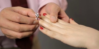 男人把漂亮的银戒指戴在女人手上，求婚，订婚