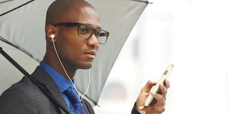 非洲黑人秃头商人使用耳麦耳机的移动电话