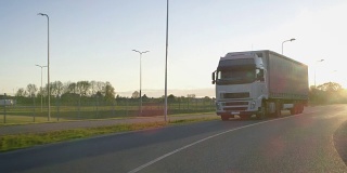在高速公路上行驶的带有货物拖车的半卡车。白色卡车通过工业仓库区域运送货物。