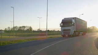 在高速公路上行驶的带有货物拖车的半卡车。白色卡车通过工业仓库区域运送货物。视频素材模板下载