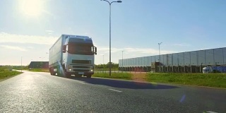 大型白色半挂车与货物拖车移动在工业仓库区域的空旷道路与阳光照耀的背景。